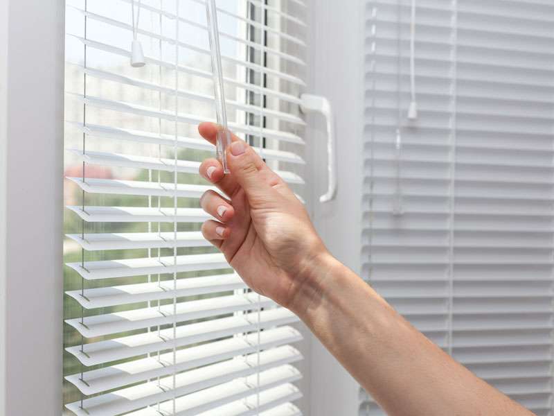 Frau öffnet Jalousien aus Cottbus